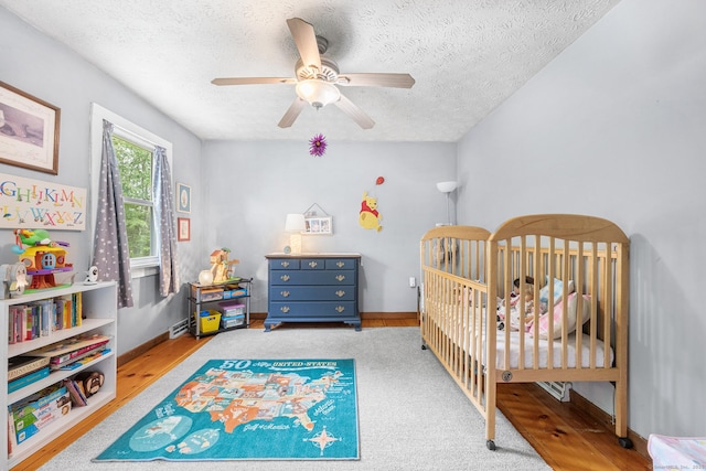 103 Pine St, Columbia, CT 06237 - bedroom with a textured ceiling, a crib, baseboards, a ceiling fan, and wood finished floors