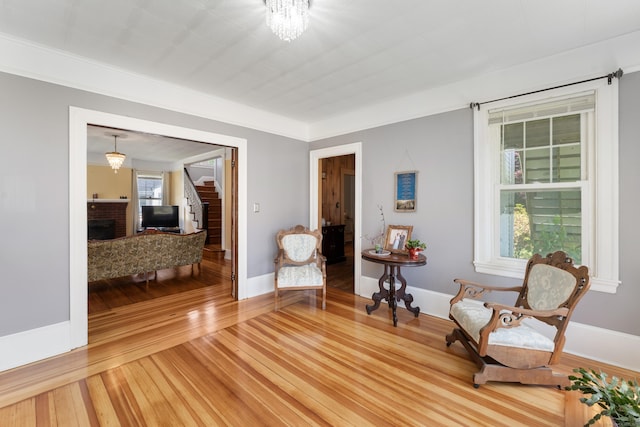 90 Broad St, Killingly, CT 06239 - sitting room featuring stairway, light wood finished floors, a brick fireplace, and a chandelier
