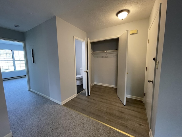 782 Oronoke Rd Apt 33, Waterbury, CT 06708 - unfurnished bedroom featuring baseboards, a closet, a textured ceiling, baseboard heating, and wood finished floors