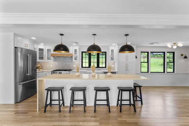 193 Stoner Dr, West Hartford, CT 06107 - kitchen featuring high end fridge, stove, white cabinetry, a breakfast bar, and ornamental molding