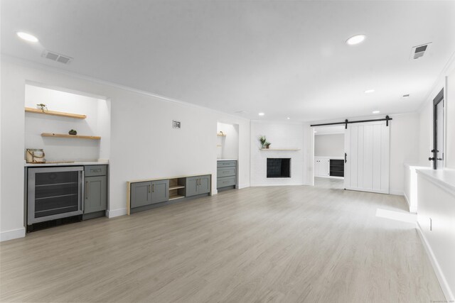 193 Stoner Dr, West Hartford, CT 06107 - unfurnished living room with beverage cooler, a barn door, ornamental molding, light wood-style floors, and a dry bar
