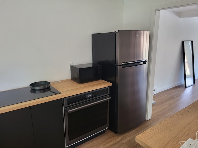 44 Tolland Ave Apt 54, Stafford, CT 06076 - kitchen featuring black appliances, dark cabinetry, light wood-type flooring, and butcher block counters
