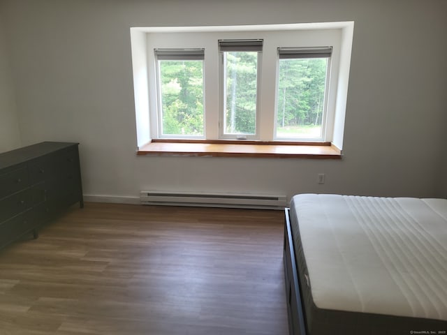 44 Tolland Ave Apt 54, Stafford, CT 06076 - unfurnished bedroom with a baseboard heating unit, multiple windows, baseboards, and wood finished floors