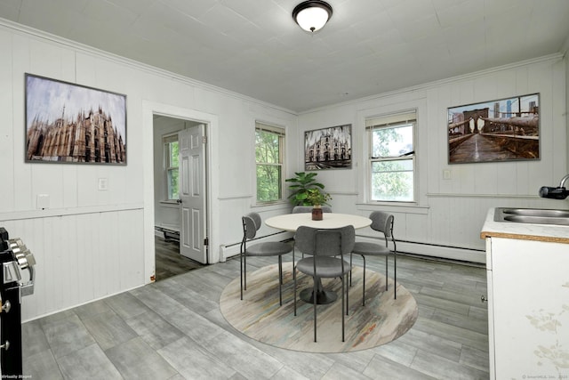 9 Woodland St, Vernon, CT 06066 - dining space featuring a baseboard heating unit, crown molding, a baseboard radiator, wood finished floors, and wood walls