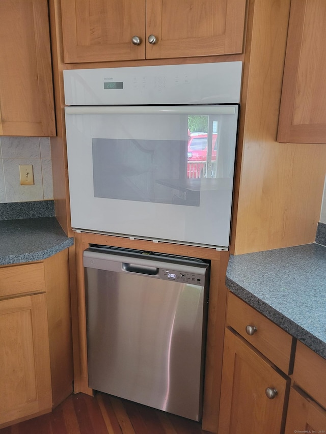 26 King St, Shelton, CT 06484 - kitchen featuring stainless steel dishwasher, oven, backsplash, dark wood-style floors, and dark countertops