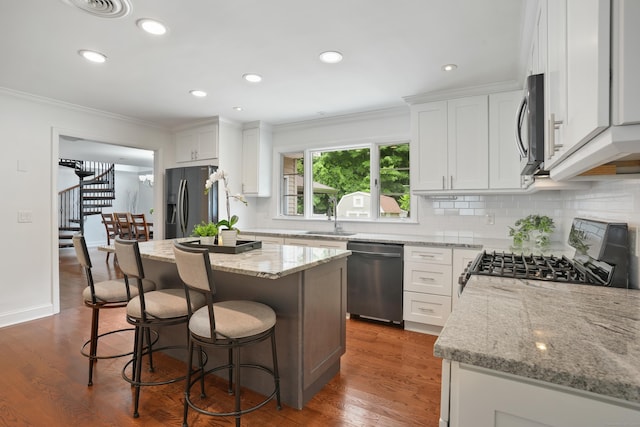 8 Palmer Ln, Oxford, CT 06478 - kitchen featuring appliances with stainless steel finishes, ornamental molding, tasteful backsplash, light stone countertops, and a breakfast bar area