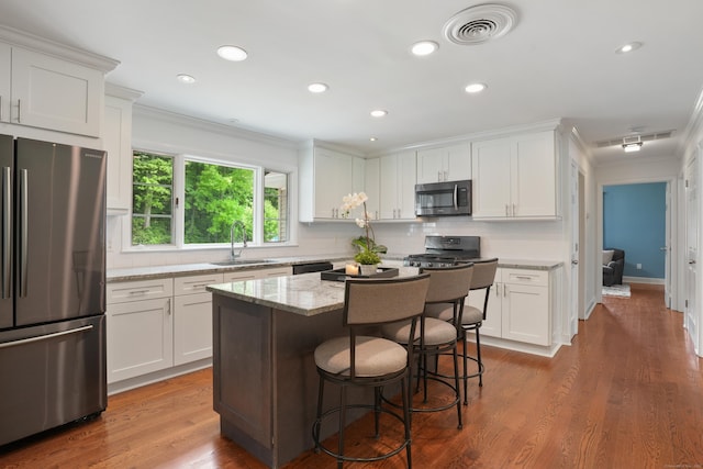 8 Palmer Ln, Oxford, CT 06478 - kitchen with appliances with stainless steel finishes, ornamental molding, white cabinetry, light stone counters, and a kitchen breakfast bar