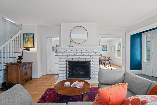 1748 Whitney Ave, Hamden, CT 06517 - living room featuring stairs, baseboards, light wood-type flooring, a brick fireplace, and crown molding