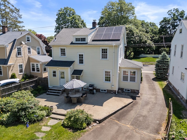 1748 Whitney Ave, Hamden, CT 06517 - back of house with solar panels, a chimney, a shingled roof, and a patio