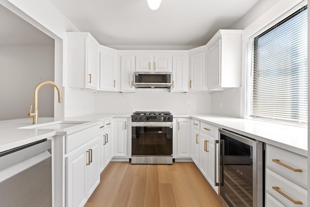 156 Apache Ln Unit A, Stratford, CT 06614 - kitchen with wine cooler, stainless steel appliances, a sink, white cabinets, and light countertops