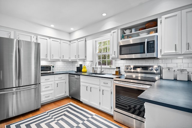 68 Blue Spruce Cir, Weston, CT 06883 - kitchen with appliances with stainless steel finishes, a sink, dark countertops, decorative backsplash, and white cabinetry