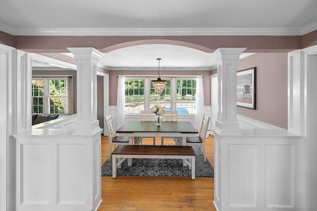 452 Burnt Plains Rd, Milford, CT 06461 - dining area featuring ornate columns, a decorative wall, light wood-type flooring, arched walkways, and ornamental molding