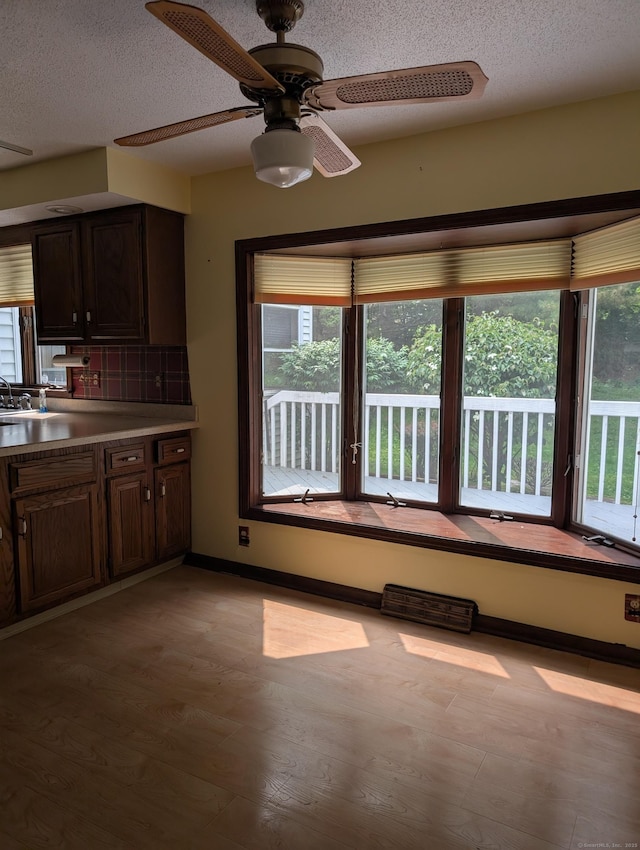 1060 Still Hill Rd, Hamden, CT 06518 - kitchen with healthy amount of natural light, ceiling fan, tasteful backsplash, a textured ceiling, and dark brown cabinetry