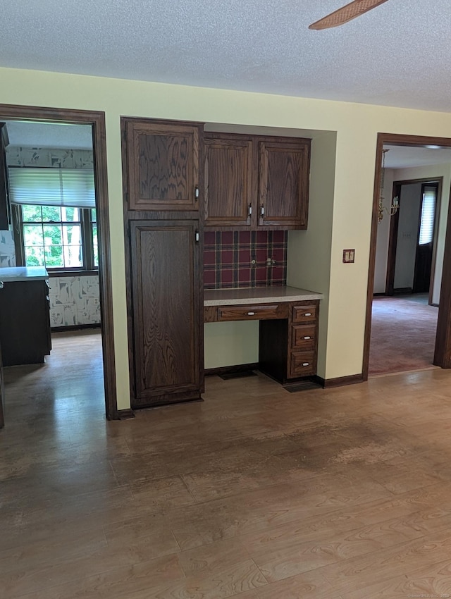 1060 Still Hill Rd, Hamden, CT 06518 - kitchen with light countertops, dark brown cabinetry, light wood-type flooring, an office area, and a textured ceiling