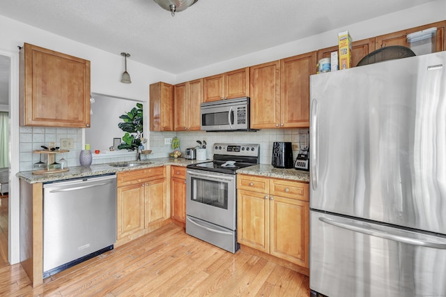 196 New Haven Ave Unit 322, Derby, CT 06418 - kitchen featuring appliances with stainless steel finishes, backsplash, light wood finished floors, light stone counters, and a sink