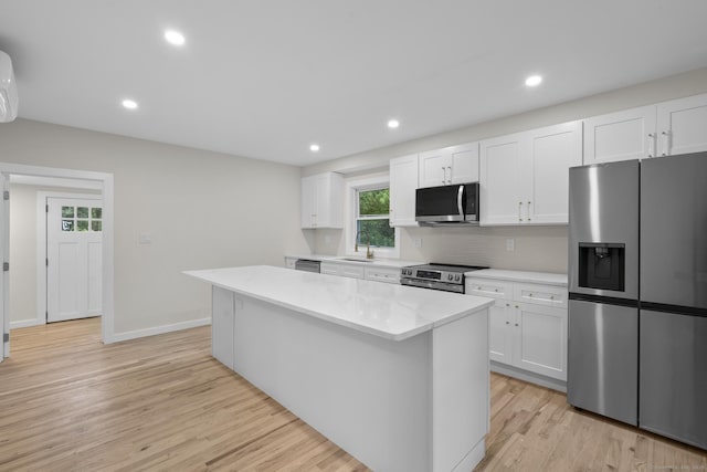 123 Lower Rd, North Canaan, CT 06024 - kitchen featuring appliances with stainless steel finishes, a kitchen island, light wood-type flooring, white cabinetry, and tasteful backsplash
