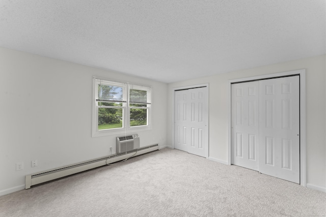 107 Greens Loop, Cheshire, CT 06410 - unfurnished bedroom featuring a baseboard radiator, multiple closets, carpet, an AC wall unit, and a textured ceiling