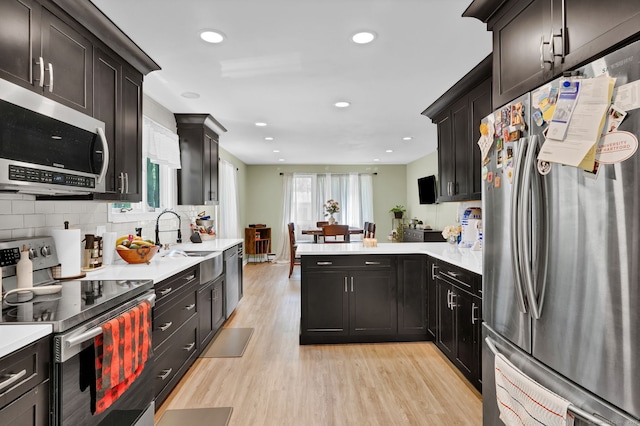 268 Cliffside Dr Unit 268, Torrington, CT 06790 - kitchen featuring appliances with stainless steel finishes, a sink, light wood-style flooring, light countertops, and a peninsula