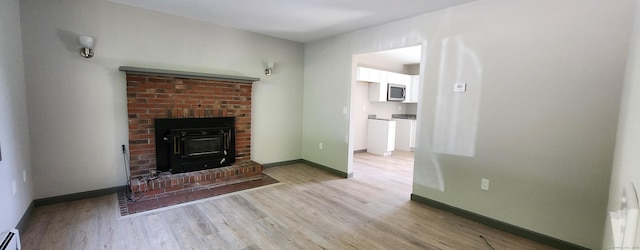 552 Squaw Rock Rd, Plainfield, CT 06354 - unfurnished living room featuring a baseboard heating unit, light wood-type flooring, baseboards, and a brick fireplace