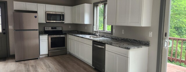 552 Squaw Rock Rd, Plainfield, CT 06354 - kitchen with appliances with stainless steel finishes, a sink, white cabinetry, and light wood-style floors