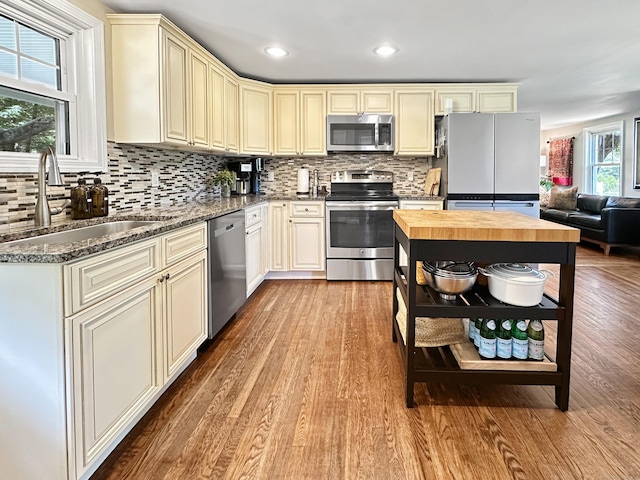 276 Boston Post Rd, East Lyme, CT 06333 - kitchen with appliances with stainless steel finishes, cream cabinetry, a sink, wood finished floors, and tasteful backsplash