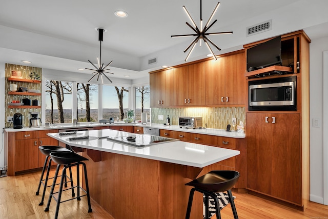 29 Montevideo Rd, Avon, CT 06001 - kitchen with stainless steel microwave, brown cabinets, black electric cooktop, light wood-type flooring, and a breakfast bar area
