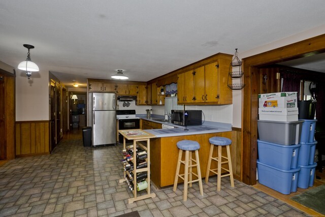42 Sycamore Ter, Windham, CT 06280 - kitchen featuring appliances with stainless steel finishes, brown cabinetry, brick patterned flooring, a peninsula, and wainscoting