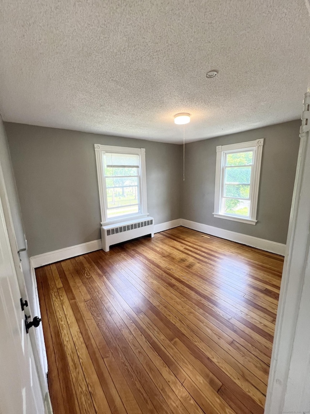 127 Smalley St, New Britain, CT 06051 - spare room featuring radiator heating unit, a textured ceiling, hardwood / wood-style floors, and baseboards