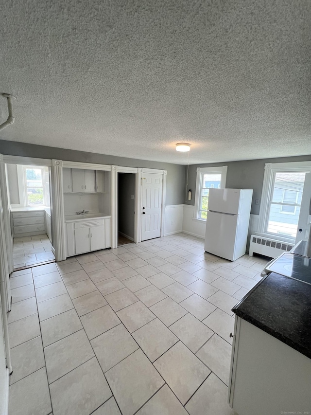 127 Smalley St, New Britain, CT 06051 - unfurnished living room with light tile patterned flooring, radiator heating unit, and a textured ceiling
