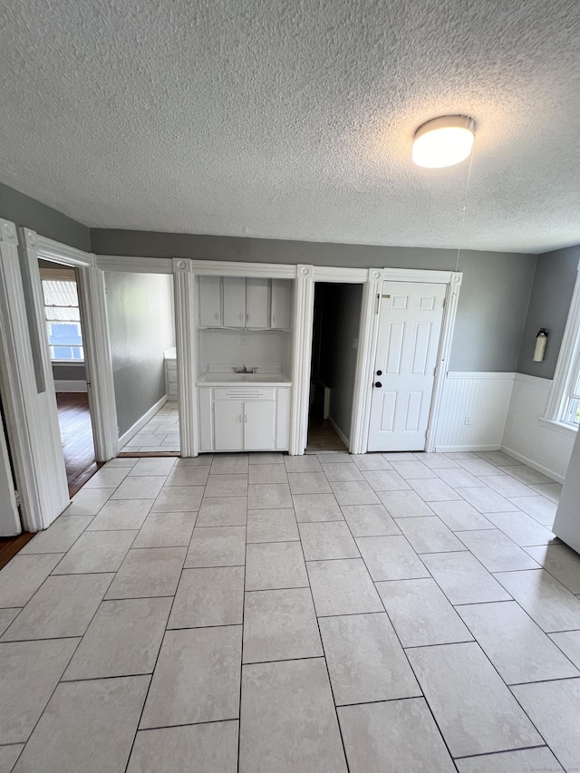 127 Smalley St, New Britain, CT 06051 - unfurnished room with a textured ceiling, wainscoting, healthy amount of natural light, and light tile patterned floors