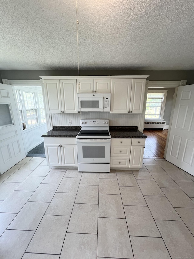 127 Smalley St, New Britain, CT 06051 - kitchen featuring white appliances, a textured ceiling, light tile patterned floors, dark countertops, and a baseboard radiator