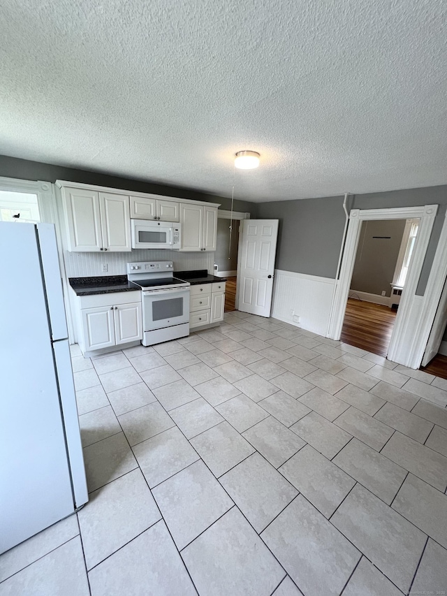 127 Smalley St, New Britain, CT 06051 - kitchen with white appliances, dark countertops, white cabinets, wainscoting, and a textured ceiling