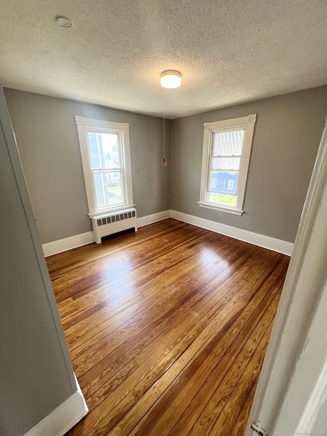 127 Smalley St, New Britain, CT 06051 - unfurnished room with radiator, plenty of natural light, wood finished floors, a textured ceiling, and baseboards