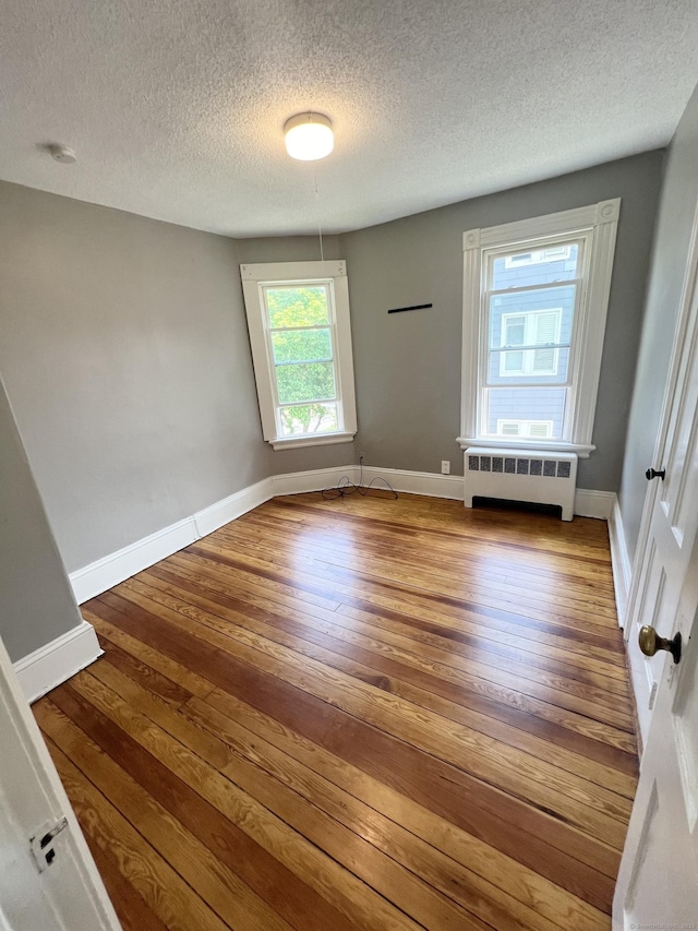 127 Smalley St, New Britain, CT 06051 - unfurnished room featuring radiator, hardwood / wood-style flooring, a textured ceiling, and baseboards