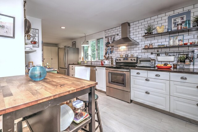 225 Rocky Mountain Rd, Southbury, CT 06488 - kitchen featuring stainless steel appliances, wall chimney range hood, dark countertops, white cabinetry, and light wood-style flooring