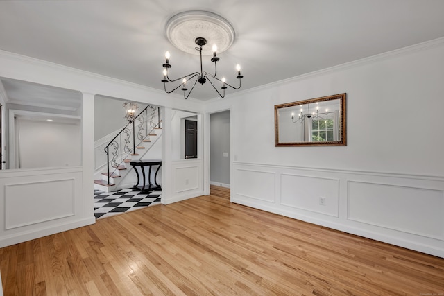 206 Ludlow Rd, Manchester, CT 06040 - unfurnished dining area with a chandelier, crown molding, a decorative wall, stairway, and light wood-style floors