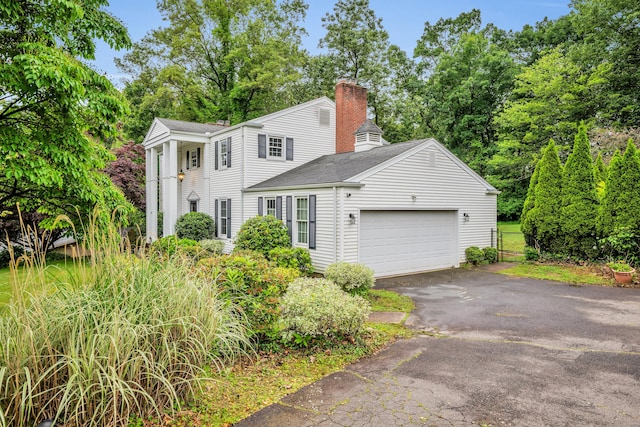 206 Ludlow Rd, Manchester, CT 06040 - view of front facade with asphalt driveway, a chimney, an attached garage, a shingled roof, and view of scattered trees