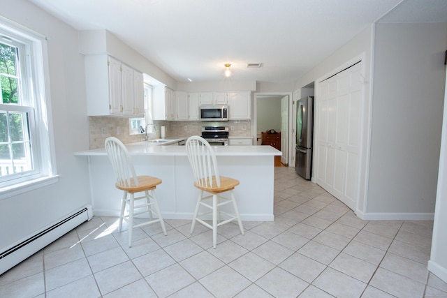 12 Northwoods Rd, Granby, CT 06060 - kitchen featuring stainless steel appliances, baseboard heating, a peninsula, light tile patterned floors, and decorative backsplash