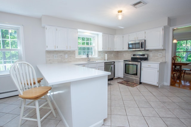 12 Northwoods Rd, Granby, CT 06060 - kitchen with stainless steel appliances, a sink, a peninsula, decorative backsplash, and white cabinetry