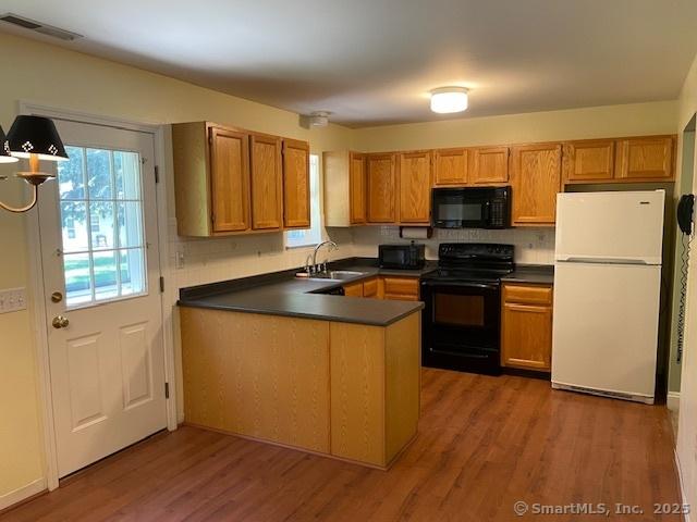 150 Forest Rd Unit 40, Milford, CT 06461 - kitchen featuring black appliances, dark countertops, a peninsula, and wood finished floors