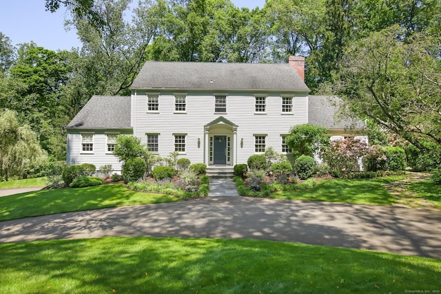 151 Woodridge Dr, New Canaan, CT 06840 - colonial home featuring a chimney, a front lawn, and roof with shingles