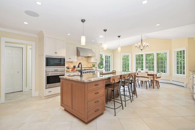 151 Woodridge Dr, New Canaan, CT 06840 - kitchen featuring wall chimney exhaust hood, a baseboard heating unit, a sink, a center island with sink, and tasteful backsplash
