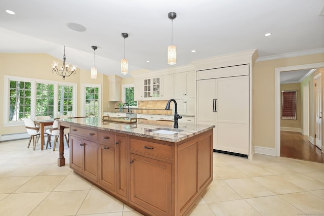 151 Woodridge Dr, New Canaan, CT 06840 - kitchen with paneled built in fridge, a sink, glass insert cabinets, light stone countertops, and a chandelier