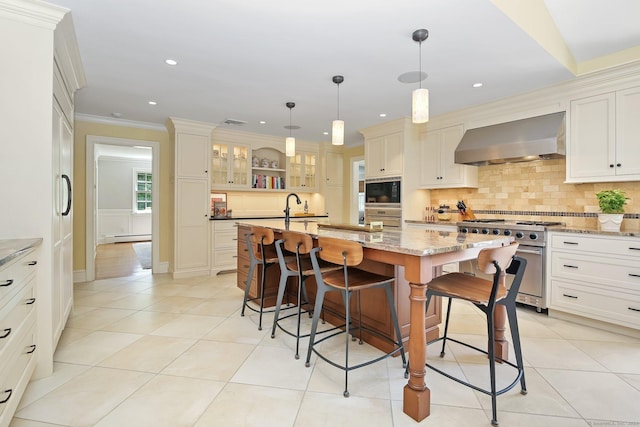 151 Woodridge Dr, New Canaan, CT 06840 - kitchen featuring wall chimney exhaust hood, stainless steel appliances, a breakfast bar, a center island with sink, and tasteful backsplash