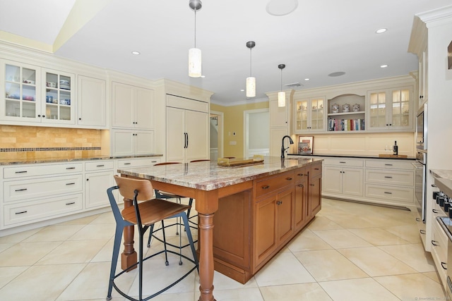 151 Woodridge Dr, New Canaan, CT 06840 - kitchen with paneled built in fridge, a center island with sink, a kitchen bar, a sink, and crown molding
