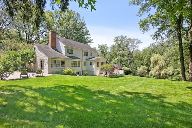 151 Woodridge Dr, New Canaan, CT 06840 - rear view of property featuring a patio, a yard, a chimney, and central AC