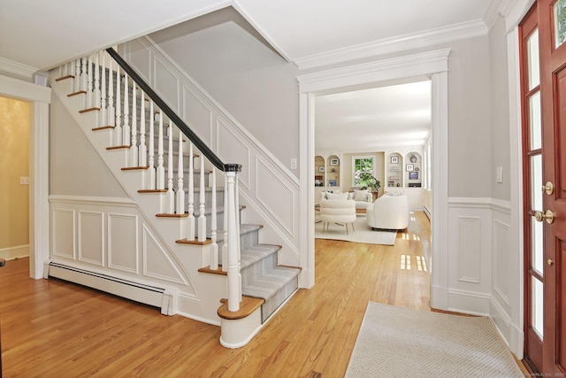 151 Woodridge Dr, New Canaan, CT 06840 - entrance foyer with a baseboard radiator, a decorative wall, light wood-type flooring, stairs, and ornamental molding