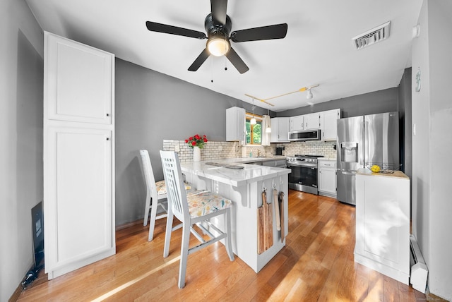 3 Celentano Dr, Naugatuck, CT 06770 - kitchen featuring appliances with stainless steel finishes, a peninsula, tasteful backsplash, white cabinets, and light wood finished floors
