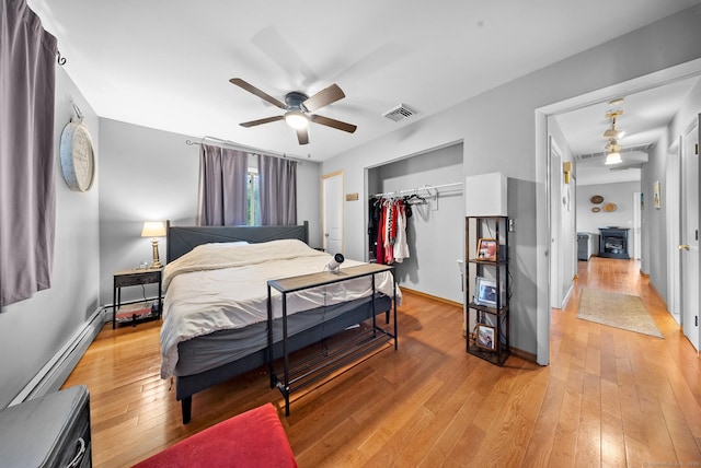 3 Celentano Dr, Naugatuck, CT 06770 - bedroom with a baseboard heating unit, light wood-style floors, a closet, a wood stove, and baseboards