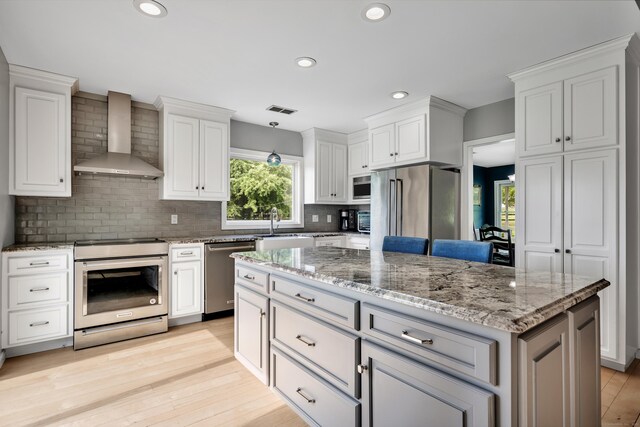 233 Church St, Hebron, CT 06231 - kitchen with stainless steel appliances, wall chimney range hood, decorative backsplash, white cabinetry, and a center island